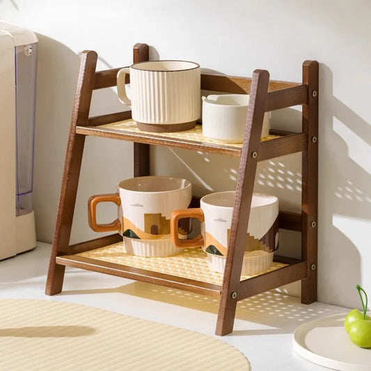 Wooden shelf with ceramic cups on a light-colored floor. 2-tier bamboo countertop organizer shelf in walnut and blonde finish, multipurpose coffee cup holder and storage rack for kitchen, bathroom, or vanity