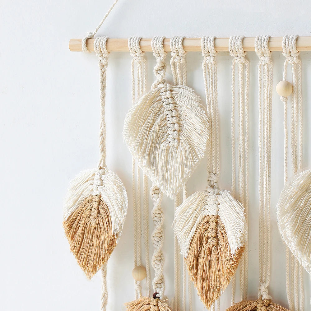 Macrame wall hanging with leaf-shaped tassels on a light background