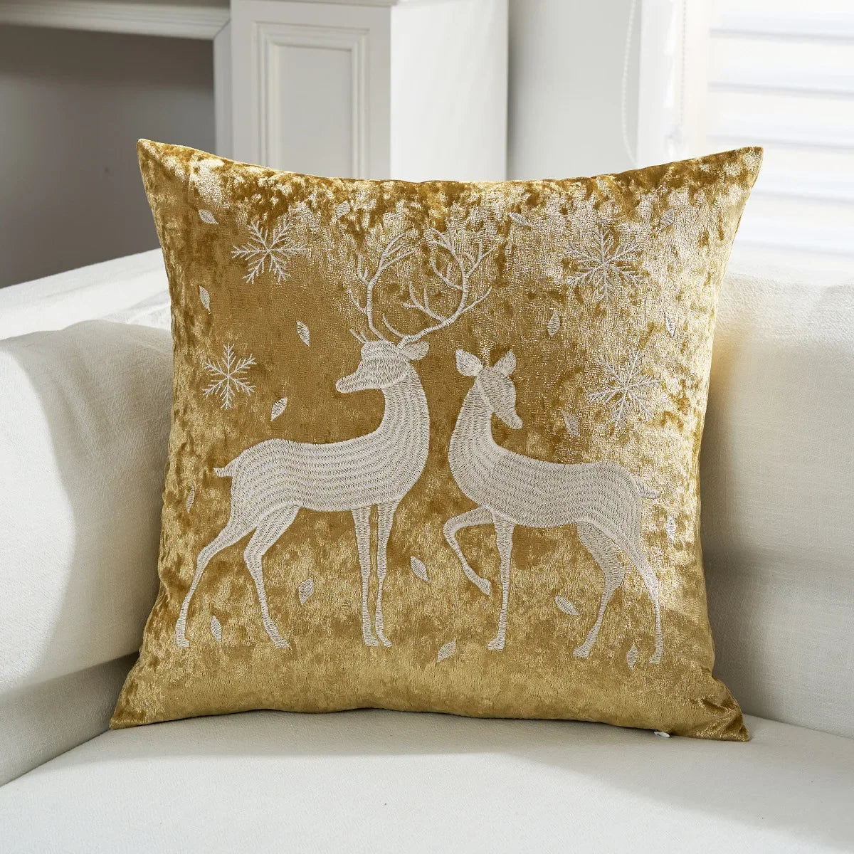 Decorative pillow with deer design on a white couch. Embroidered Merry Christmas pillow cover with snowflake design – festive red and white holiday cushion for sofa or bedroom décor.