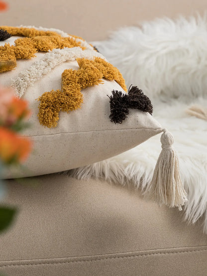 Decorative pillow with pom-poms and tassels on a beige sofa