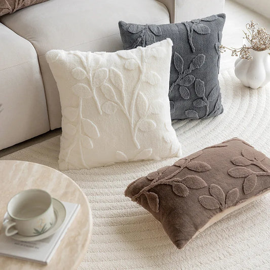 Decorative pillows on a sofa with a cup and saucer on a small table. Modern jacquard leaf throw pillow cover, woven floral decorative cushion for sofa, bed, or living room in neutral and soft tones.