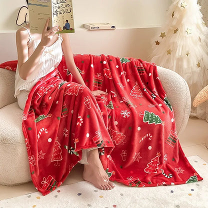 Person sitting on a couch under a red Christmas-themed blanket