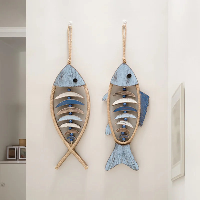Two fish-shaped wall decorations hanging on a white wall. boho home decor, coastal home accents, nautical wall hanging, wooden fish wall decor, Mediterranean decor, beach house decoration, rustic fish ornament, vintage boho living room decor, seaside wall art, summer housewarming gift
