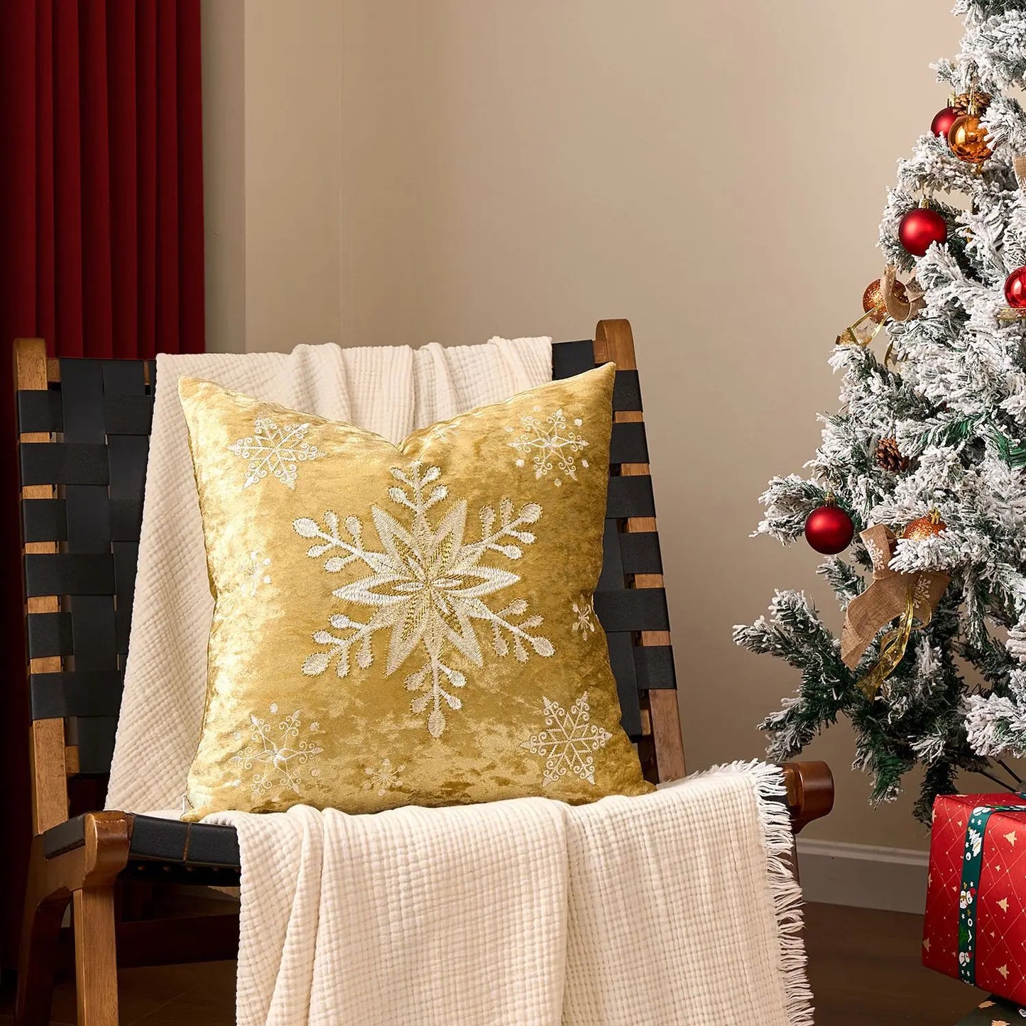 Yellow pillow with snowflake design on a chair next to a decorated Christmas tree. Embroidered Merry Christmas pillow cover with snowflake design – festive red and white holiday cushion for sofa or bedroom décor.