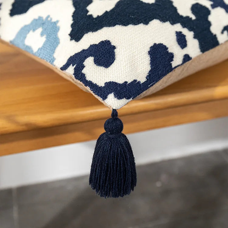 Decorative pillow with a tassel on a wooden surface. Bohemian embroidered throw pillow cover with geometric design, cotton-blend cushion for sofa, bed, or modern home decor.