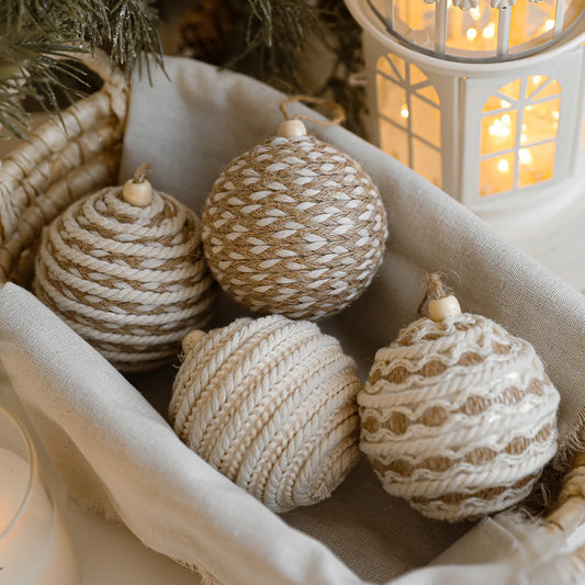 Decorative Christmas balls made of natural materials in a basket with a warm light in the background.