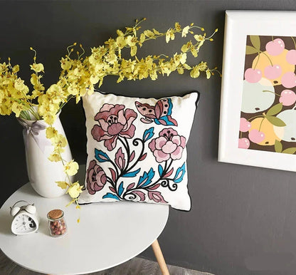 Decorative pillow with floral design on a table against a gray wall with a framed picture. floral embroidery on linen cotton cushion cover – boho home decor accent