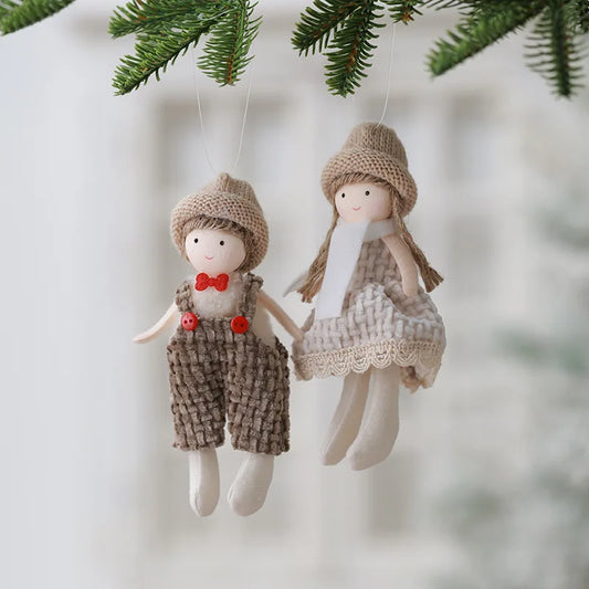 Two small dolls in knitted outfits hanging from a branch with a blurred background