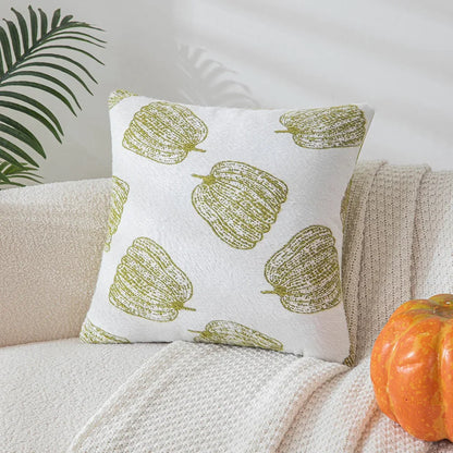 Decorative pillow with green leaf pattern on a beige couch with a pumpkin and plant in the background. Cozy fall pumpkin pillow cover for living room or bedroom