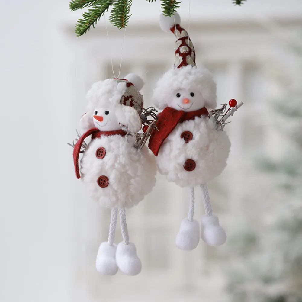 Two snowman ornaments hanging on a branch with a blurred snowy background