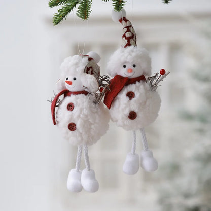 Two snowman ornaments hanging on a branch with a blurred snowy background