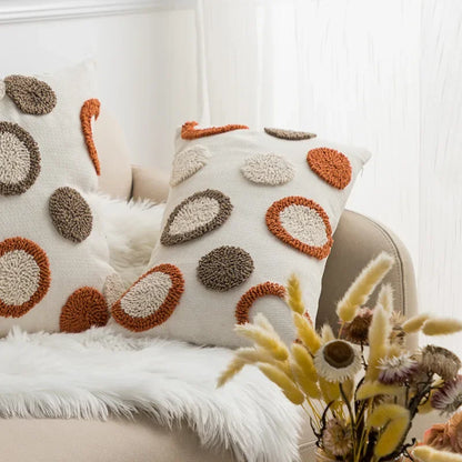 Decorative pillows with circular patterns on a sofa next to a vase of flowers. Nordic blue tufted cushion cover with geometric stripe and grid crochet pattern, tassel pillow cover for sofa, bed, and boho home decor