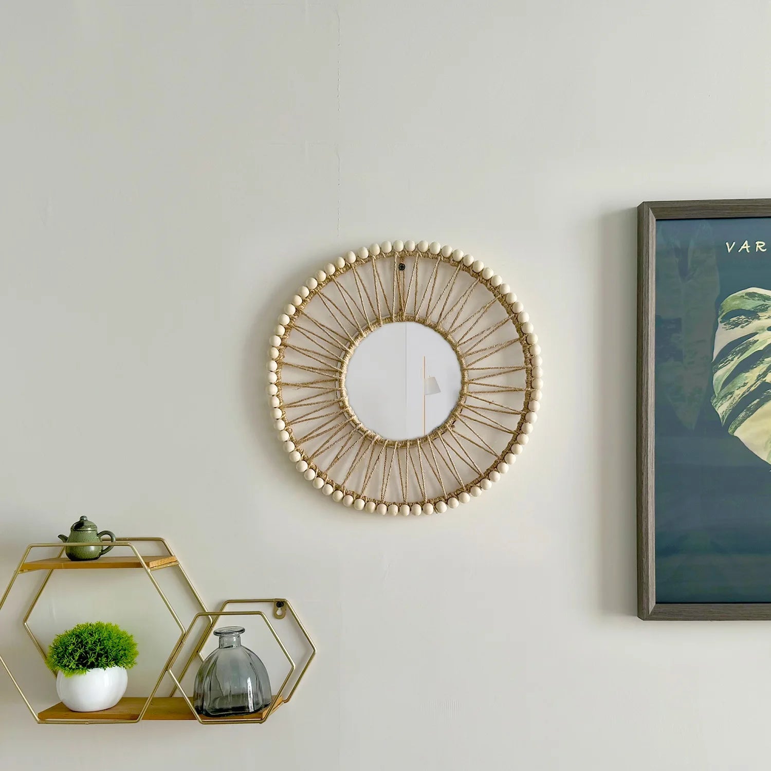 Decorative wall mirror with a geometric shelf and framed artwork on a light gray wall. Hand-woven Nordic round decorative mirror with Lafite grass frame and hemp rope, boho wall hanging for living room, entryway, or bedroom decor