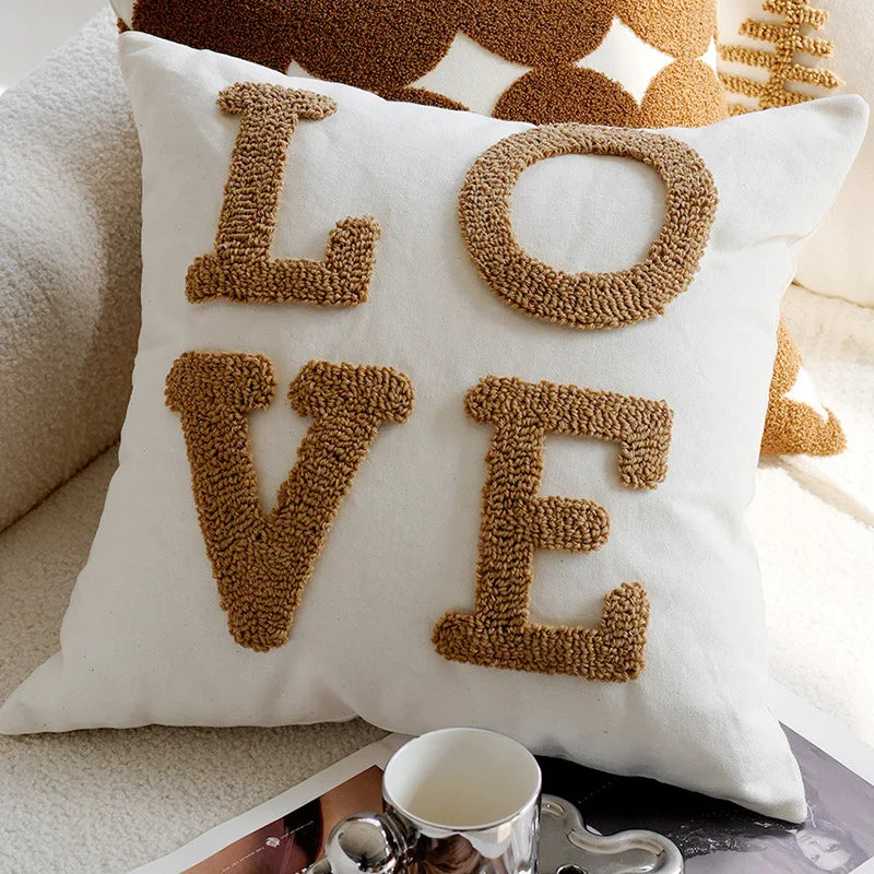 White pillow with brown 'LOVE' letters on a couch