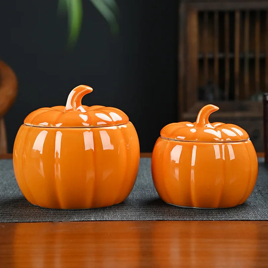Two orange pumpkin-shaped ceramic jars on a wooden surface with a blurred background. Ceramic pumpkin candy jar with lid, decorative fall tea jar or wedding gift container for home or halloween holiday decor.