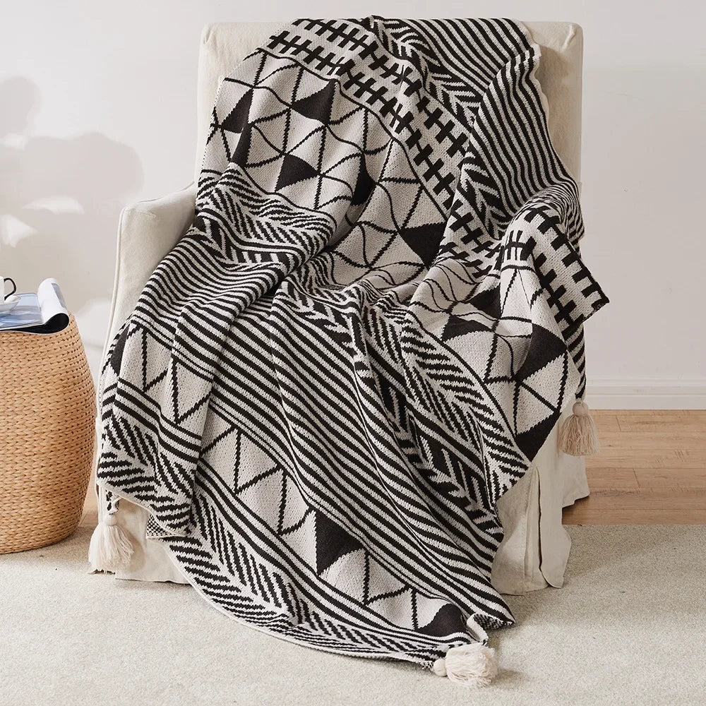 Bohemian Black and white patterned blanket draped over a chair in a room with a woven basket.