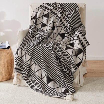 Bohemian Black and white patterned blanket draped over a chair in a room with a woven basket.