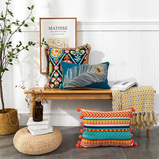 Decorative pillows on a wooden bench with a plant and framed art in the background. Bohemian embroidered throw pillow cover with geometric design, cotton-blend cushion for sofa, bed, or modern home decor.