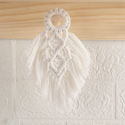 Macrame wall hanging with tassels on a textured white wall.