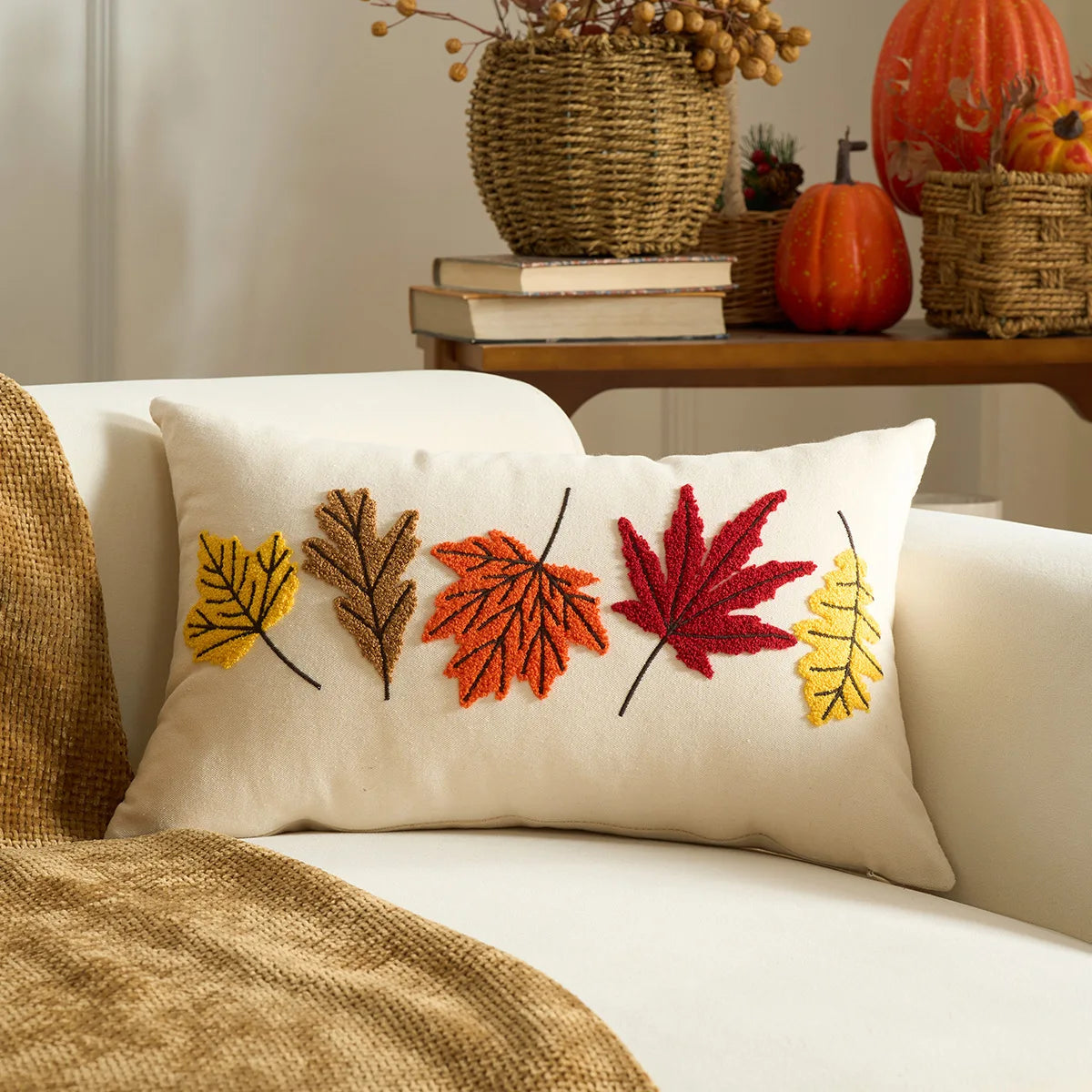 Decorative pillow with embroidered leaves on a couch, with pumpkins and books in the background. Halloween and Thanksgiving decorative pillow cover For Fall