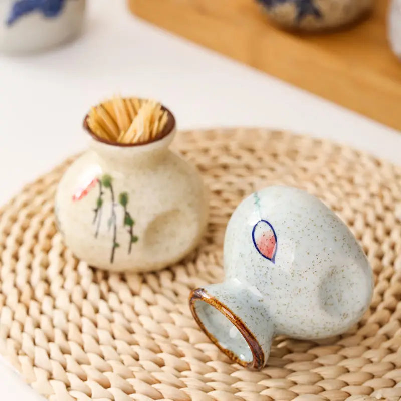 Small ceramic pots with decorative elements on a woven mat
