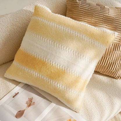 Yellow and white striped pillow on a beige couch with a woven basket.