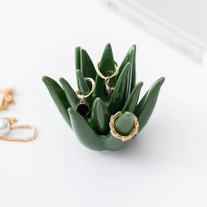 Green ceramic jewelry holder with earrings on a white background. modern ceramic aloe cactus ring and earring storage tray