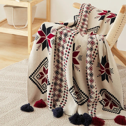 Decorative boho winter blanket with geometric snowflake patterns draped over a chair in a room.