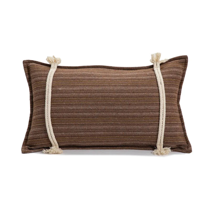 Brown pillow with white rope accents on a white background