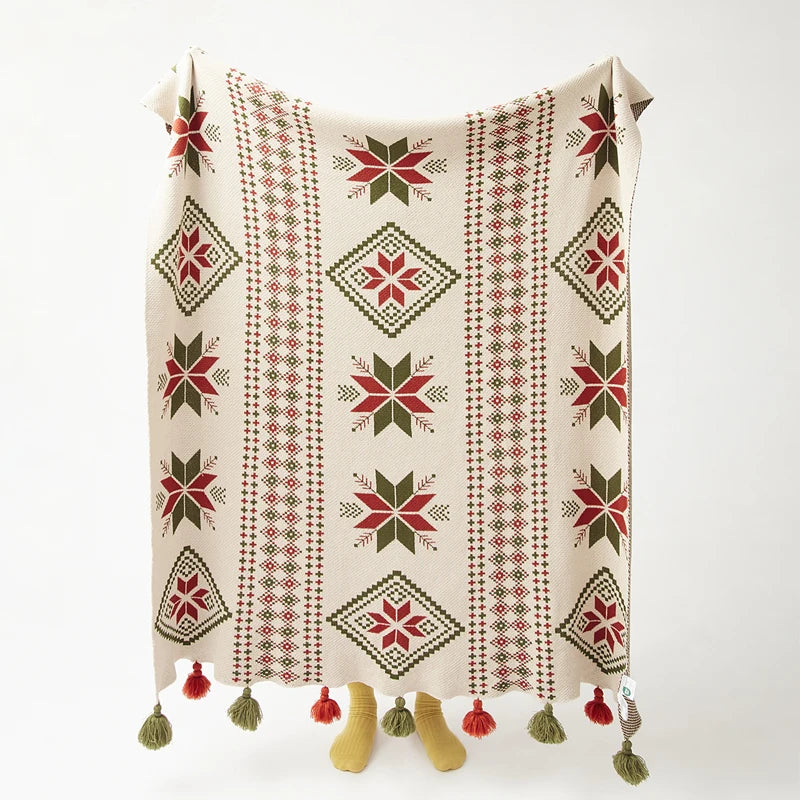 Decorative blanket with geometric snowflake winter pattern and tassels on a white background