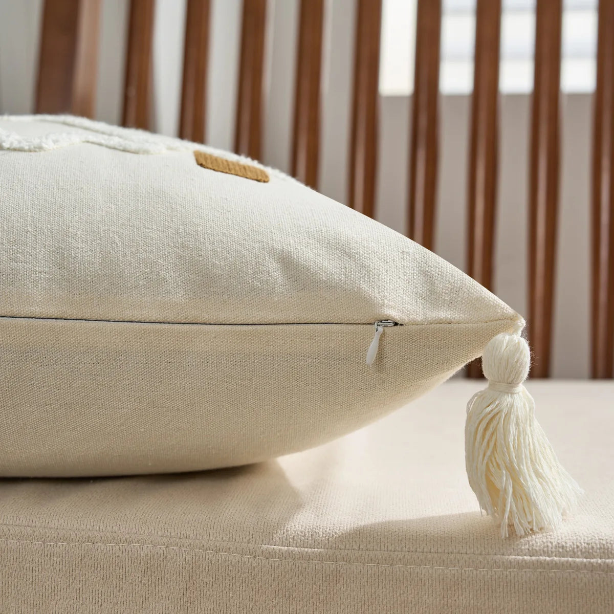 Beige pillow with tassel on a beige couch against a wooden slat wall. tufted Christmas pillow cover with tassels, decorative festive cushion case for sofa or bed in 12x20 or 18x18 inches.