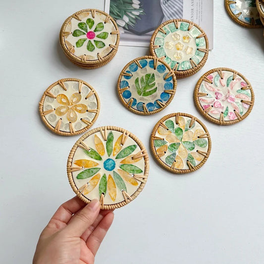 Decorative coasters with floral patterns held by a hand on a light background