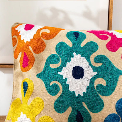 Decorative pillow with colorful abstract pattern on a beige background. Bohemian embroidered throw pillow cover with geometric design, cotton-blend cushion for sofa, bed, or modern home decor.