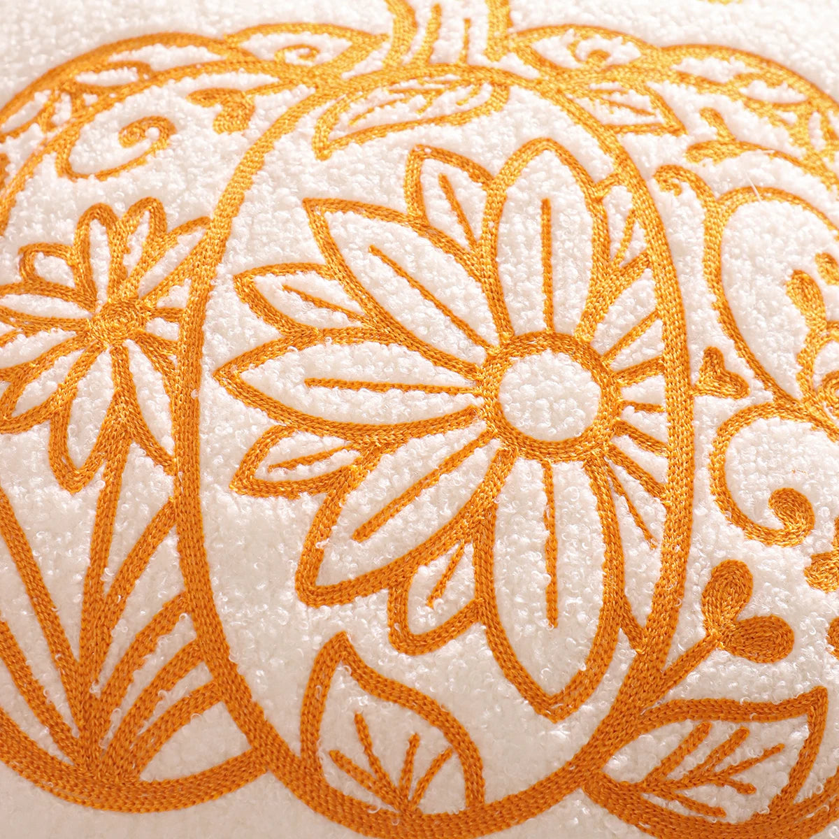 Close-up of orange floral embroidery on a beige fabric background. fall boho pillow throw gift ideas