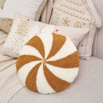Round pillow in shape of peppermint candy in gold and white pattern on a soft surface