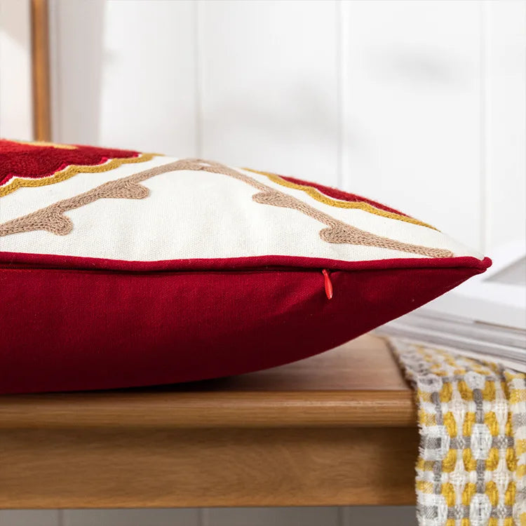 Decorative pillow with red, white, and gold colors on a wooden surface. Bohemian embroidered throw pillow cover with geometric design, cotton-blend cushion for sofa, bed, or modern home decor.