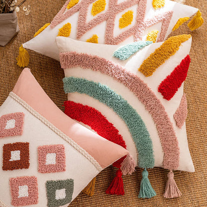 Decorative pillows with geometric patterns and tassels on a textured surface. Tufted bohemian throw pillow cover with geometric embroidery and tassels
