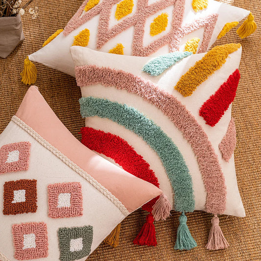 Decorative pillows with geometric patterns and tassels on a textured surface. Tufted bohemian throw pillow cover with geometric embroidery and tassels
