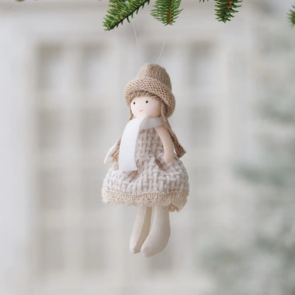 Decorative angel figurine with a knitted hat and dress hanging against a blurred natural background.