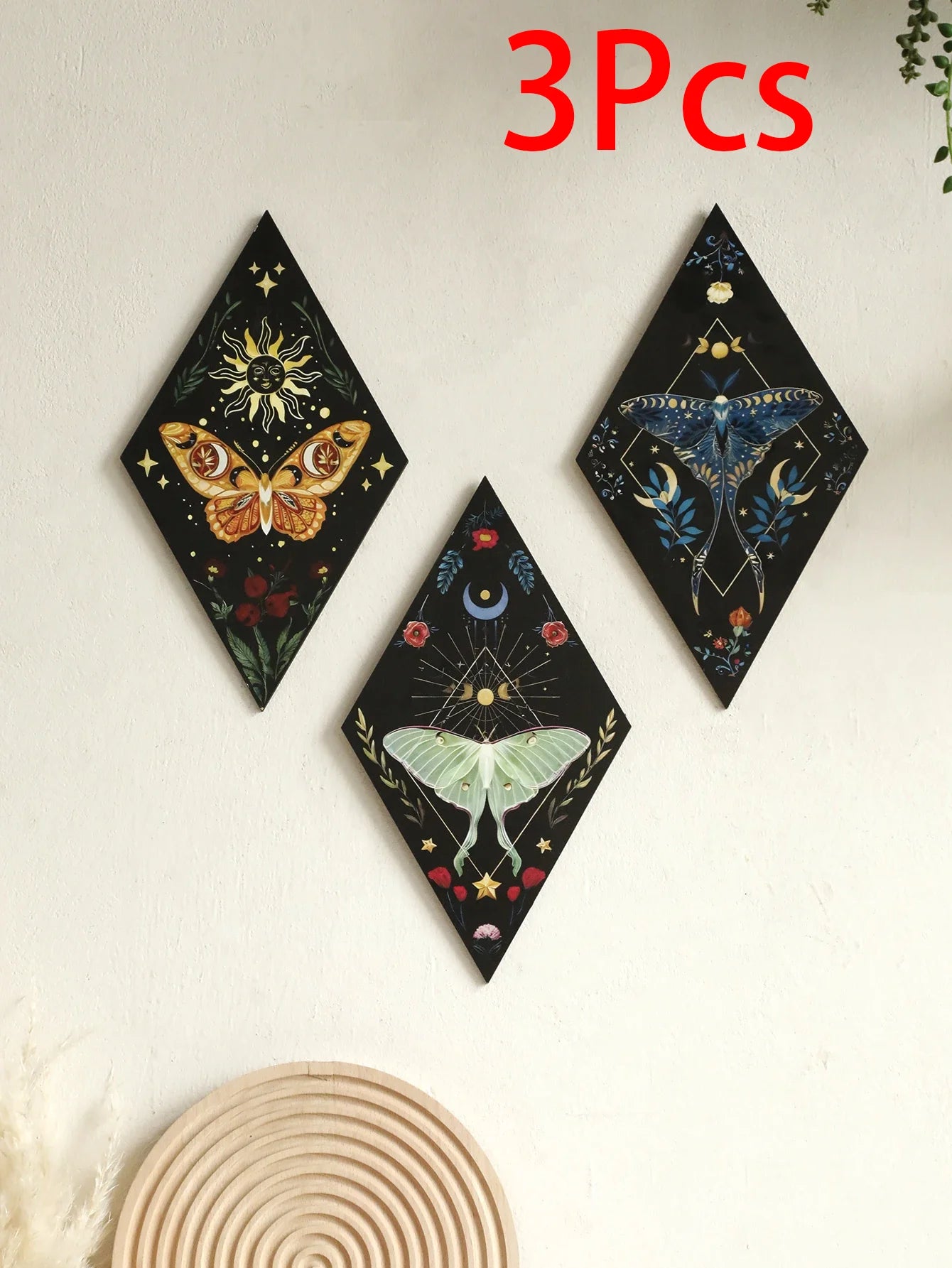 Three decorative wall art pieces with celestial designs on a light background. Rustic colorful wood wall art panel with moon, stars, and butterfly engraving, displayed above a sofa in a boho-styled living room