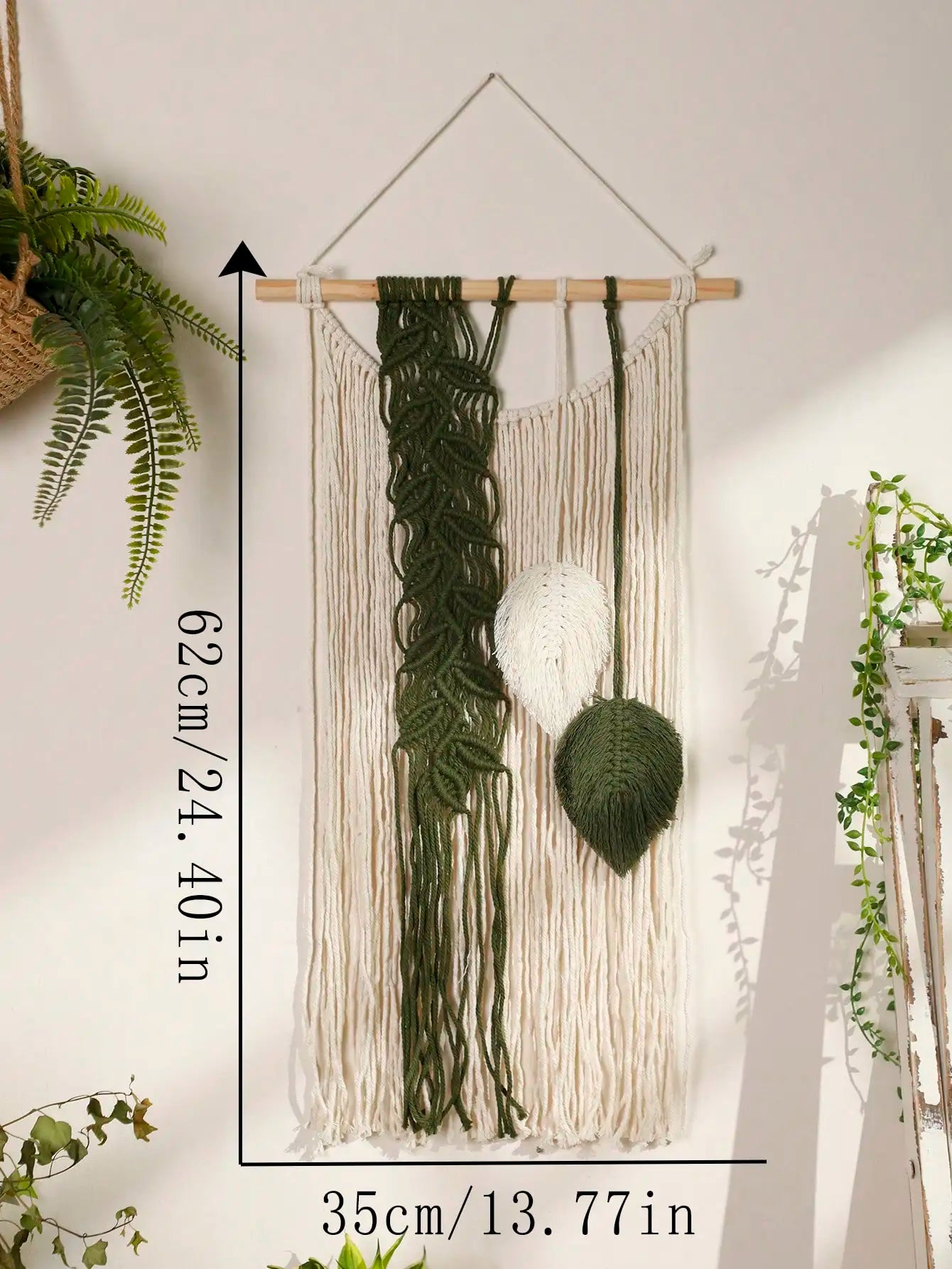 Macrame boho wall hanging with green and white elements on a plain wall.