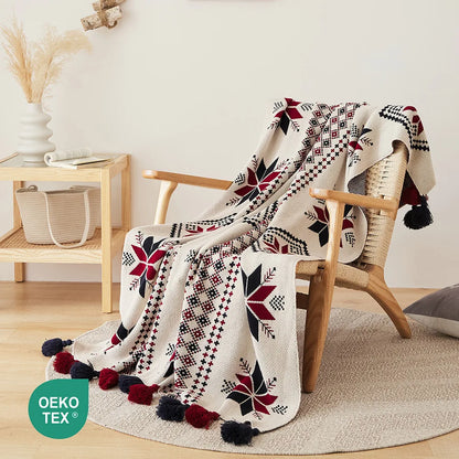 Decorative blanket with geometric patterns draped over a chair in a room setting, featuring the OEKO-TEX logo.
