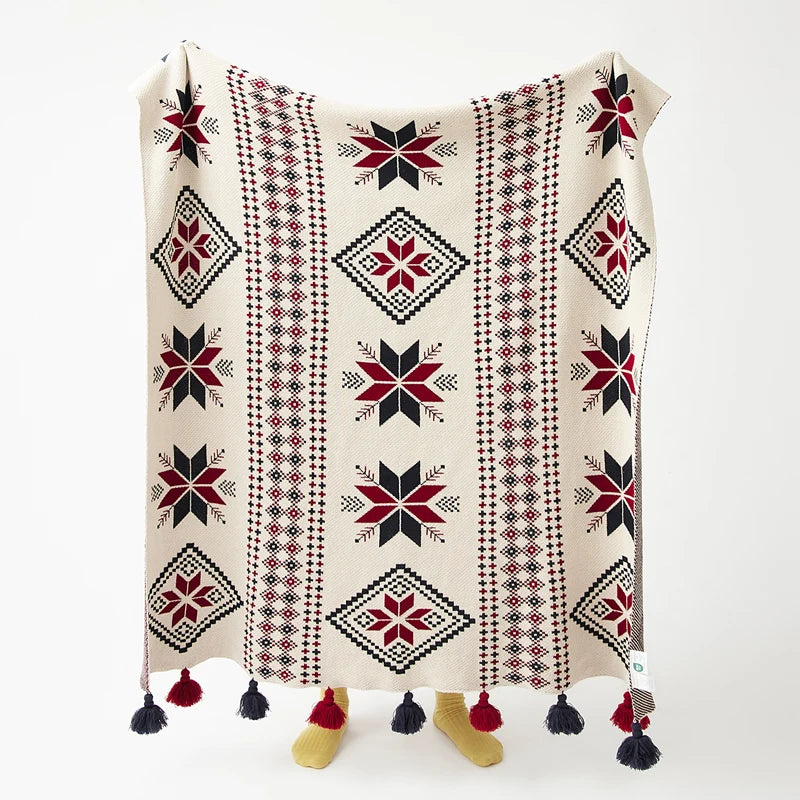 Decorative boho blanket with geometric snowflake pattern and tassels on a white background