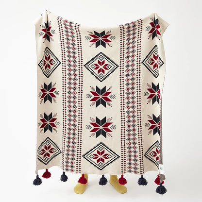 Decorative boho blanket with geometric snowflake pattern and tassels on a white background