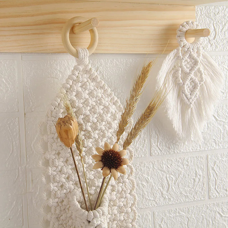 Macrame wall hanging with dried flowers and plants on a textured white wall.