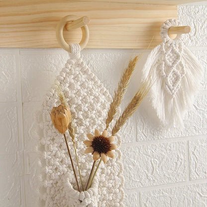 Macrame wall hanging with dried flowers and plants on a textured white wall.