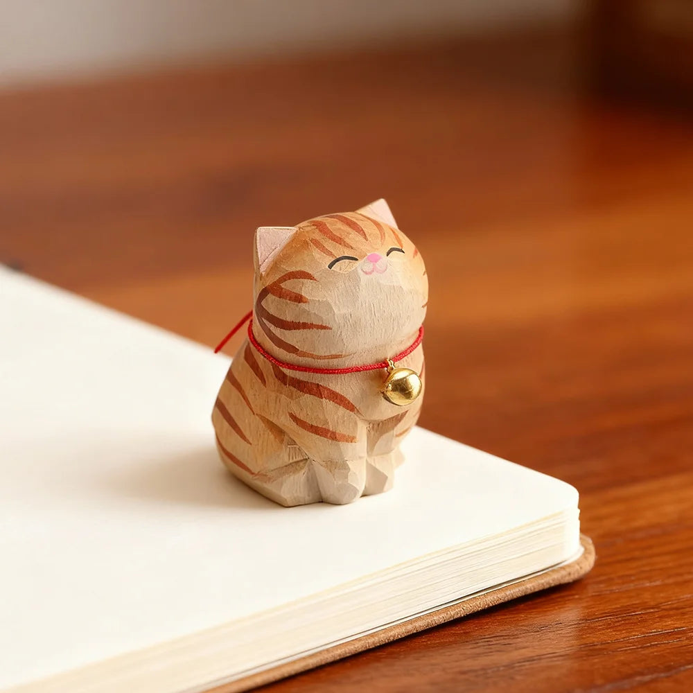 Wooden cat figurine with a red string and gold bell on an open book.