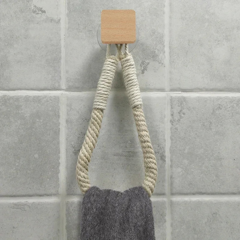 Towel hanging from a wooden hook on a tiled wall. Boho rope toilet paper holder, nail-free wall mounted paper towel rack, rustic bathroom storage and decor accessory with wood and rope design