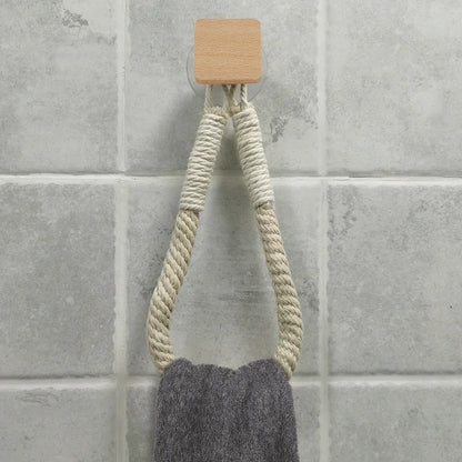 Towel hanging from a wooden hook on a tiled wall. Boho rope toilet paper holder, nail-free wall mounted paper towel rack, rustic bathroom storage and decor accessory with wood and rope design