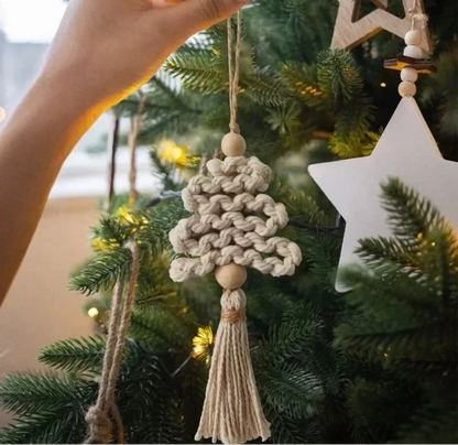 Hand holding a braided macrame Christmas tree ornament on a decorated tree with a blurred background.
